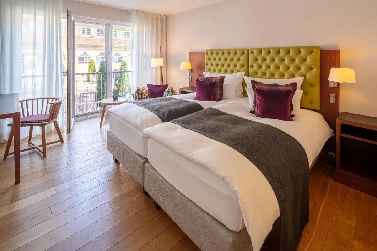 Großes Doppelbett mit dunkelroten Samtkissen im hellen Comfort-Zimmer des Waldhotels.