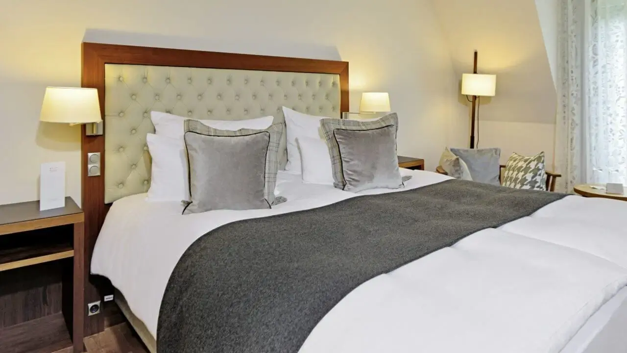 Elegantes Hotelzimmer für eine Übernachtung in Stuttgart mit großem Doppelbett, weicher Bettwäsche und gemütlichen Lampen.