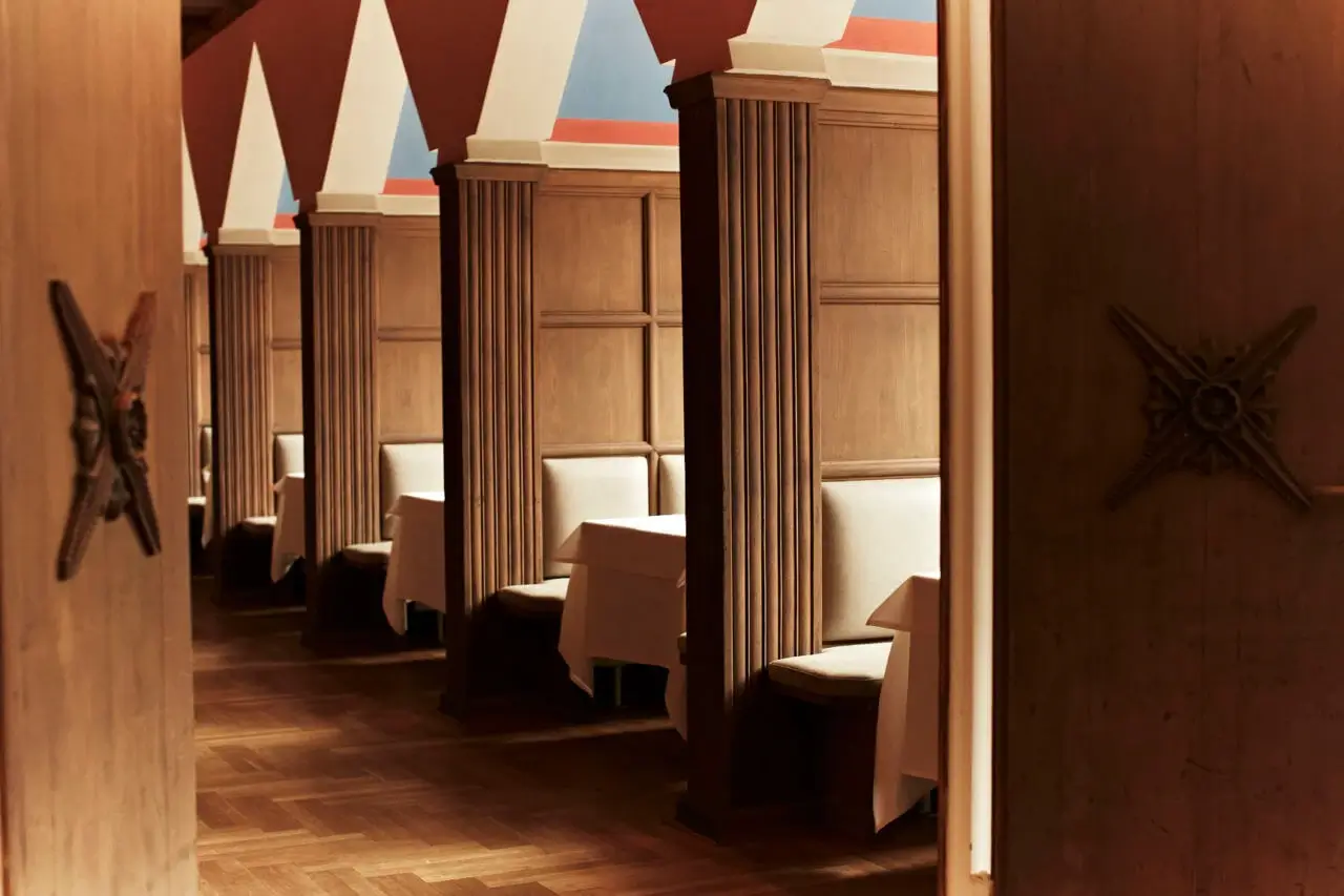 Gemütliche Nischen mit Holzverkleidung und bunt bemalten Giebeln in einem eleganten Restaurant mit Terrasse in Stuttgart.