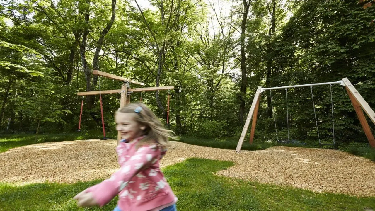Ein Spielplatz im Grünen eines Hotels in Stuttgart, umgeben von Natur.