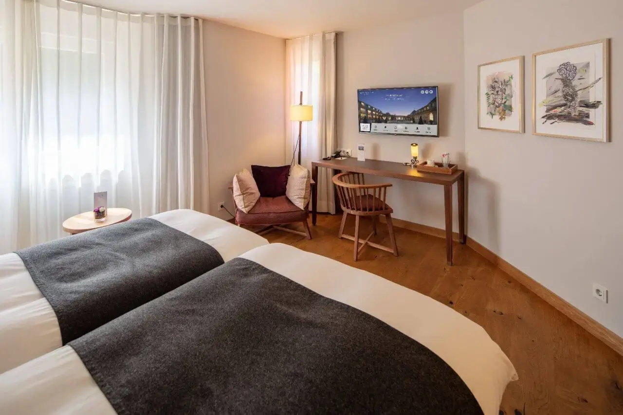 Ein modernes Hotelzimmer mit zwei Betten, Schreibtisch und gemütlicher Sitzecke.