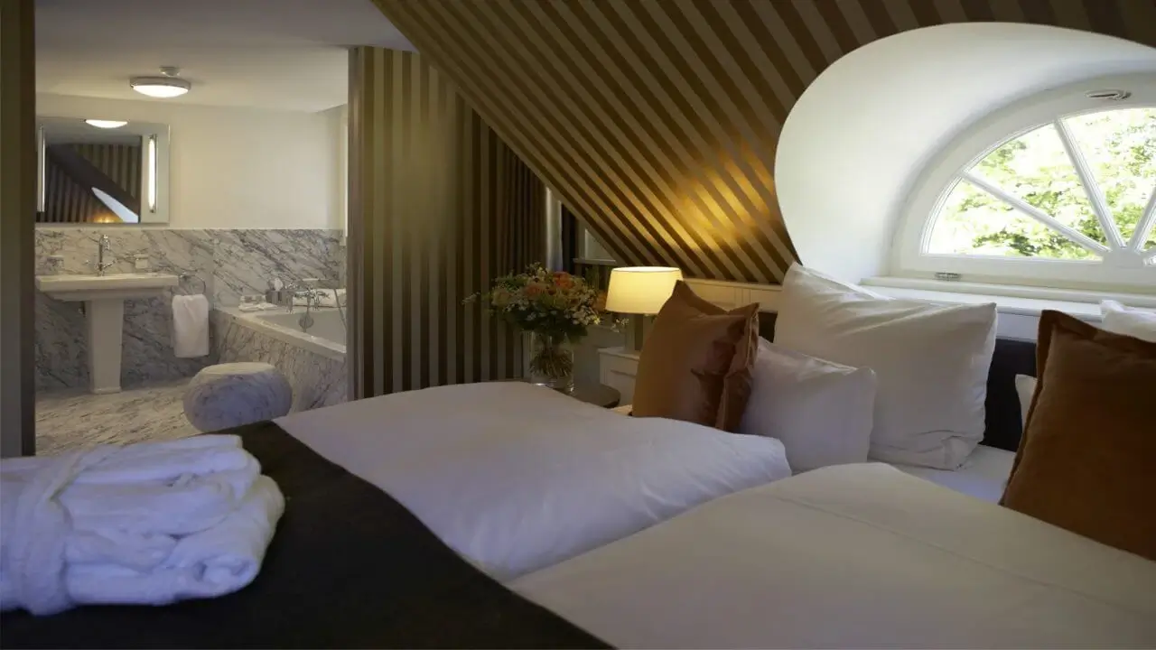 Gemütliches Hotelzimmer unter dem Dach mit Marmorbad und weichen Kissen.