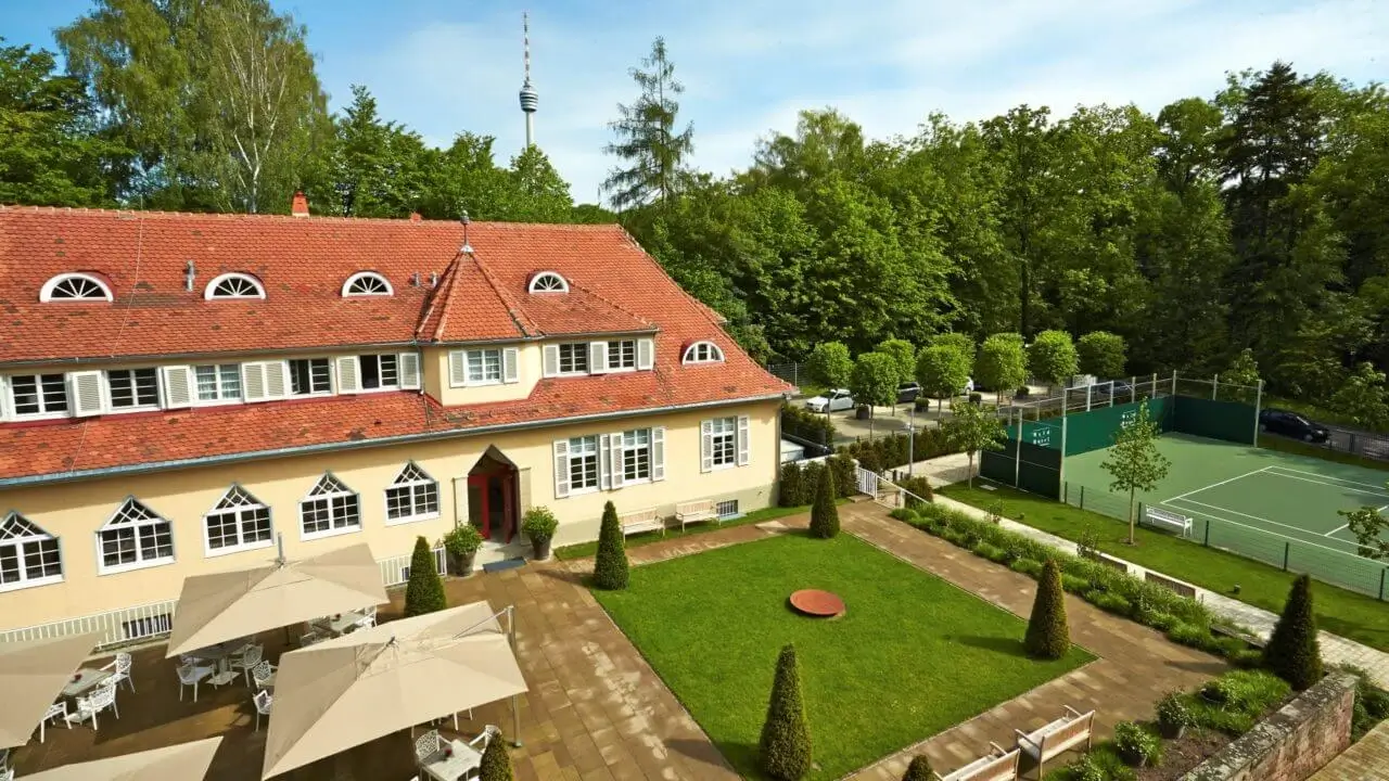 Das Waldhotel Stuttgart mit Innenhof, Sonnenterrasse und angrenzendem Tennisplatz umgeben von viel Grün.