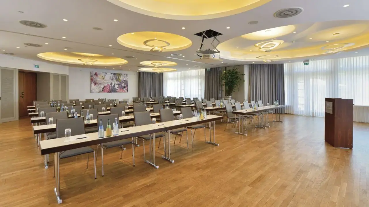 Moderner Konferenzraum im Tagungshotel in Stuttgart, ausgestattet mit Tischen, Stühlen und audiovisueller Technik.
