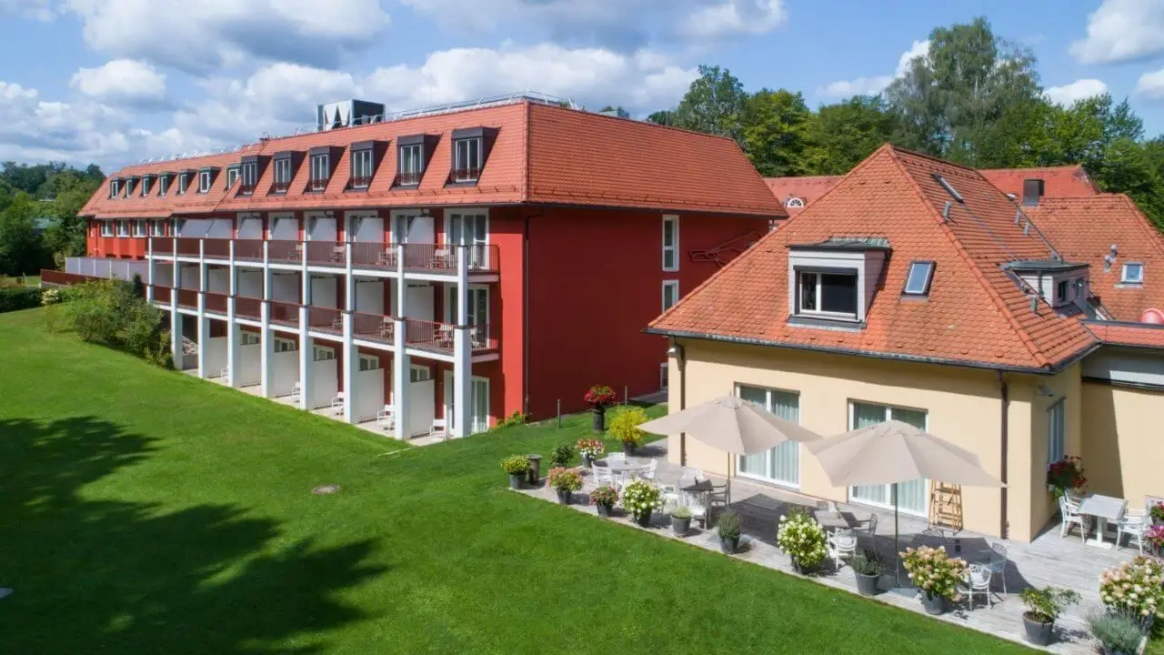 Rückansicht des Tagungshotel in Stuttgart mit grünem Rasen, Balkonen und Terrassen mit Sonnenschirmen.