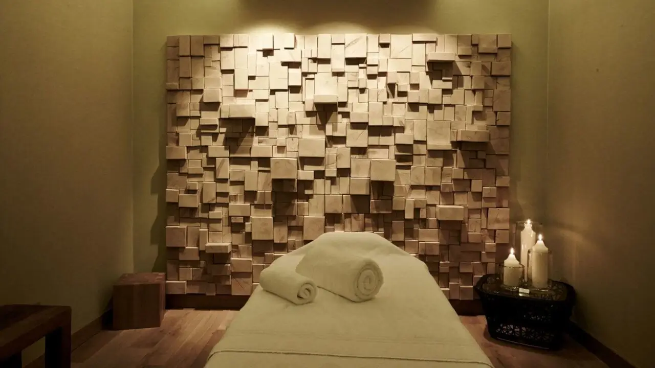 Behandlungsraum eines Hotels mit Sauna in Stuttgart mit einer Holzkunstwand und einer Massagebank.