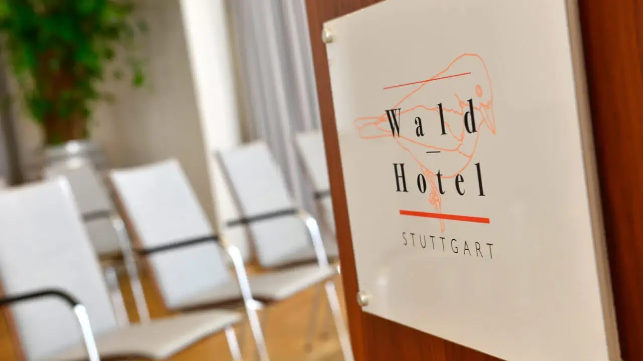 Detailaufnahme des Rednerpults im Tagungshotel in Stuttgart mit Hotel-Logo, im Hintergrund sind bequeme Stühle in einem hellen Tagungsraum zu sehen.