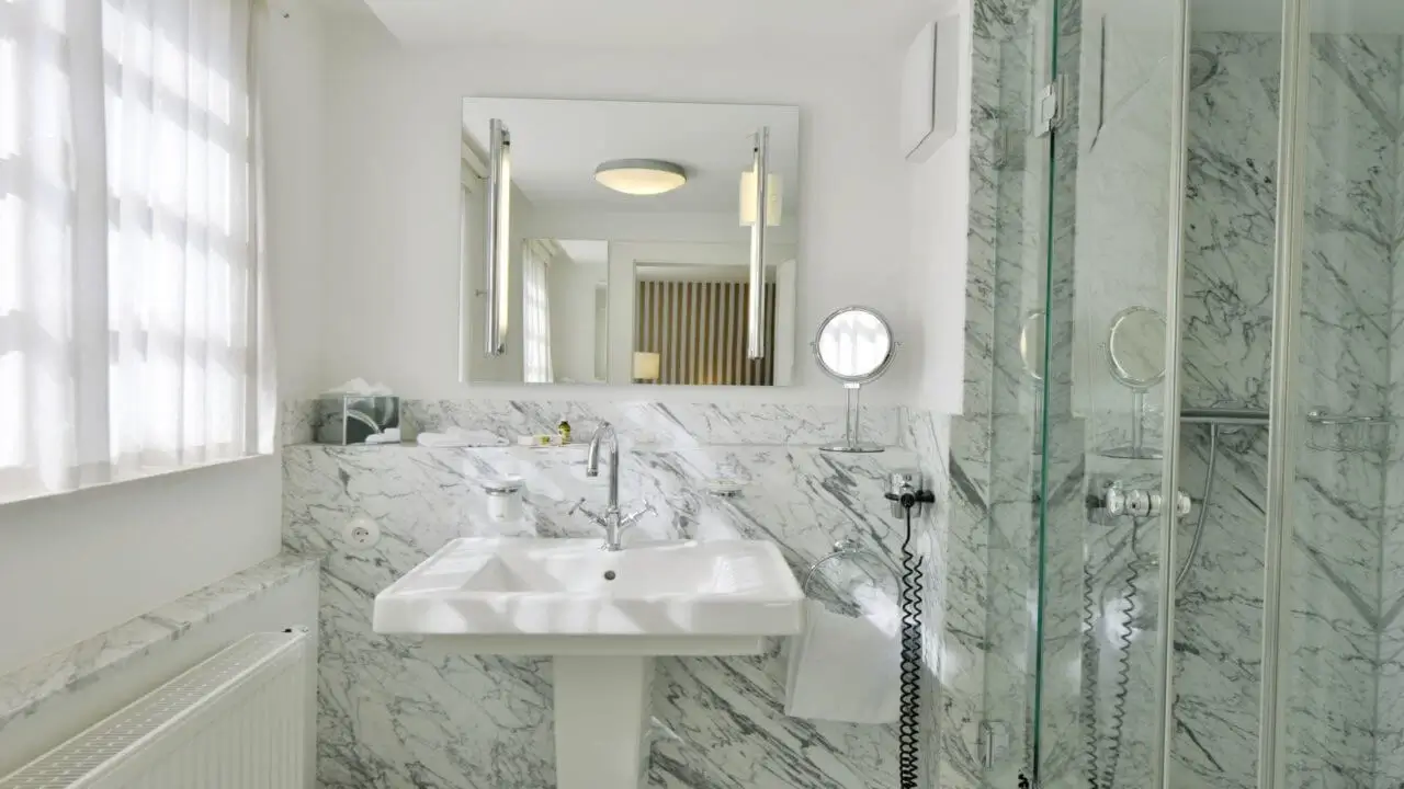 Ein modernes Badezimmer mit Marmorwänden, eleganten Armaturen und einem großen Spiegel.