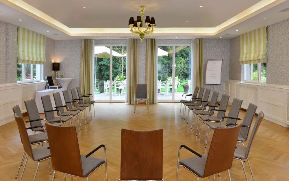 Blick durch einen Stuhlhalbkreis aus dem Lindensaal ins Grüne