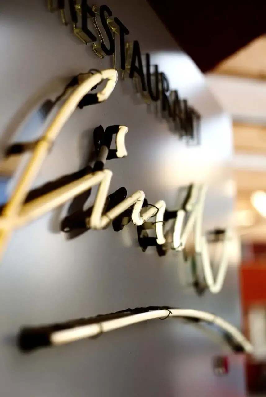 Detailaufnahme eines beleuchteten Schildes des Restaurants Finch im Hotel mit Terrasse in Stuttgart, das eine stilvolle und einladende Atmosphäre vermittelt.