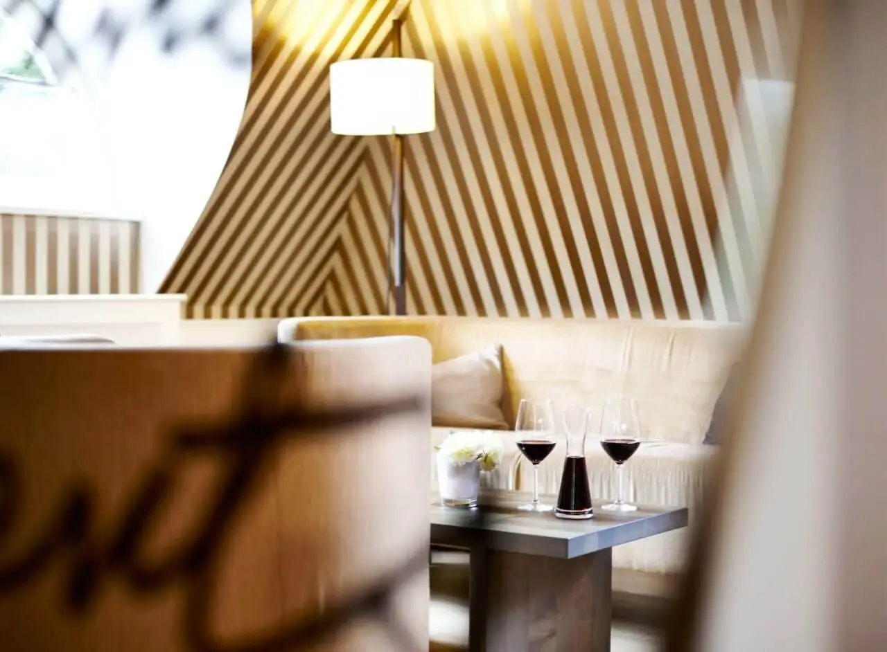 Ein stilvoller Loungebereich im 4 Sterne Hotel in Stuttgart mit gemütlichen Sesseln, einem kleinen Tisch mit Weingläsern und einem modernen, gestreiften Wanddesign.